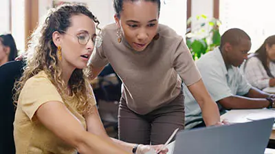 Epic Quotes  Two women working together on a computer while in an office