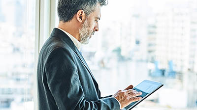 Man using tablet device while standing at window