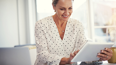 A woman smiling while using a smart tablet 